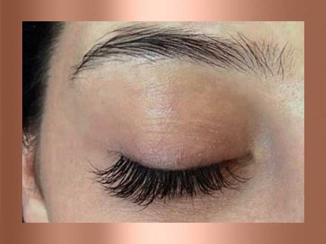 Close-up of a closed eye with long, curled eyelashes.