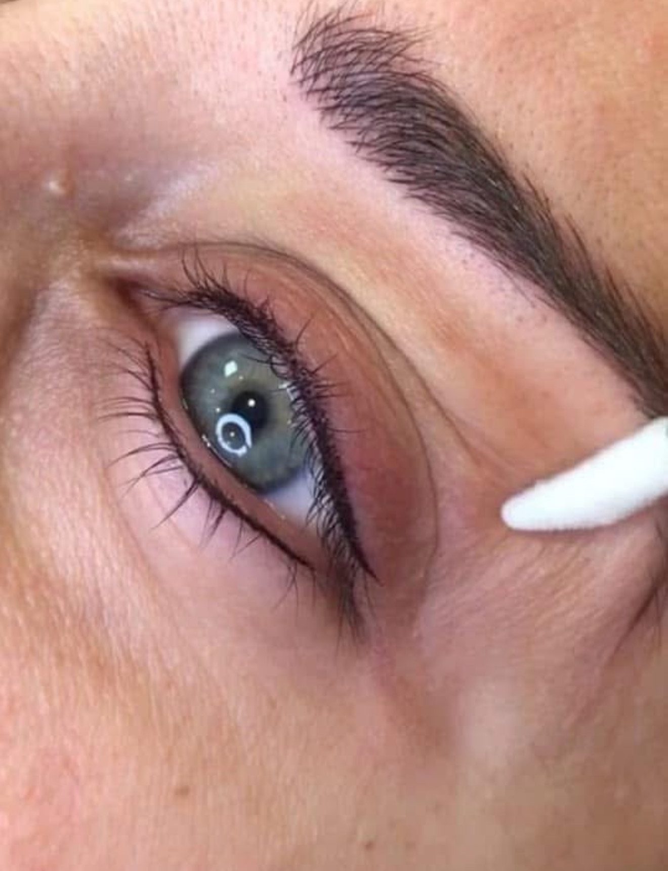 Close-up of an eye with eyeliner being applied using a cotton swab.