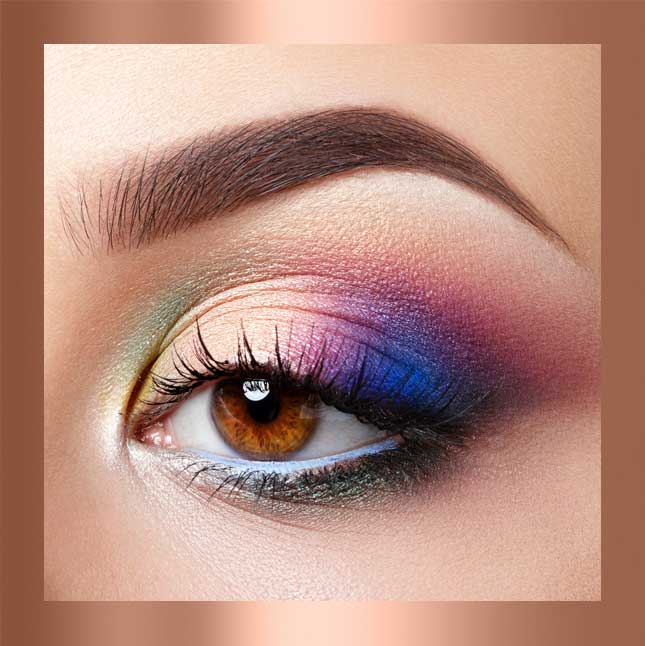 Close-up of an eye with colorful, artistic eyeshadow and well-defined eyebrow.